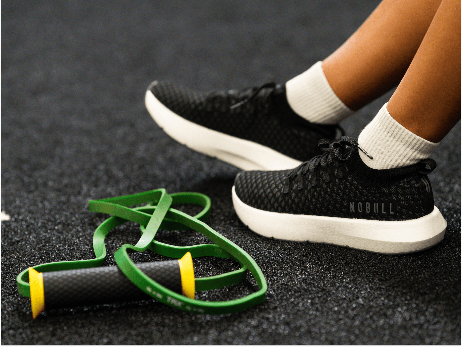 woman wearing black drive knit shoes alongside a TRX Bandit