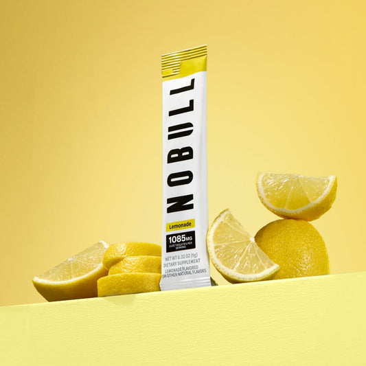 NOBULL lemonade electrolyte stick with lemon slices on a yellow background