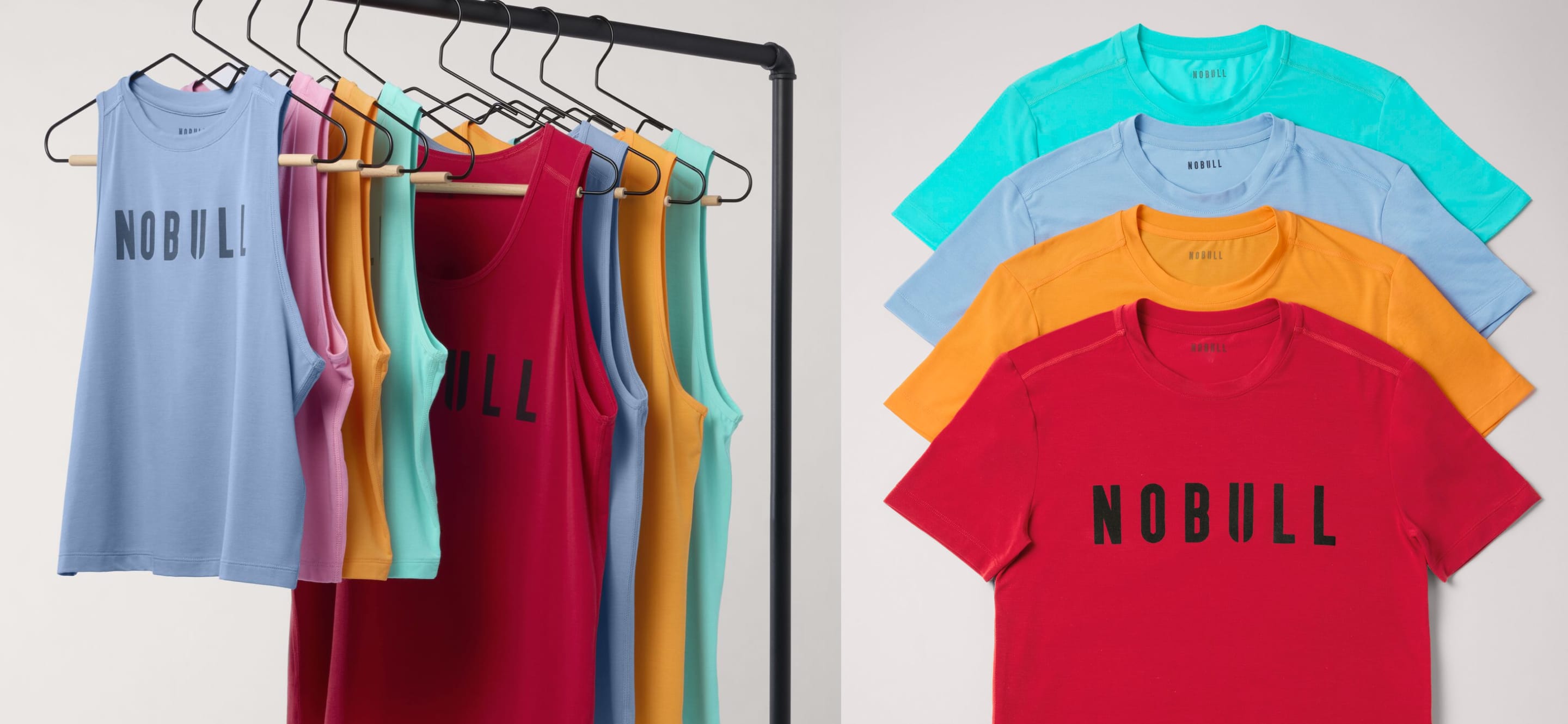 promo - A clothing rack and stack of sleeveless tank tops and short-sleeve T-shirts in multiple colors, each printed with the word 'NOBULL' across the chest. The garments are shown in light blue, pink, yellow, red, turquoise, and light blue