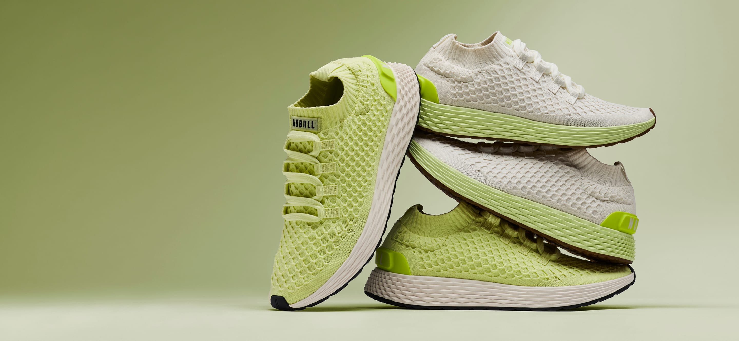 promo - Allday Knit Shoes in a stacked studio arrangement on a soft green background. The shoes feature a textured knit upper in light lime green and white, with a thick white midsole and small neon green accents.