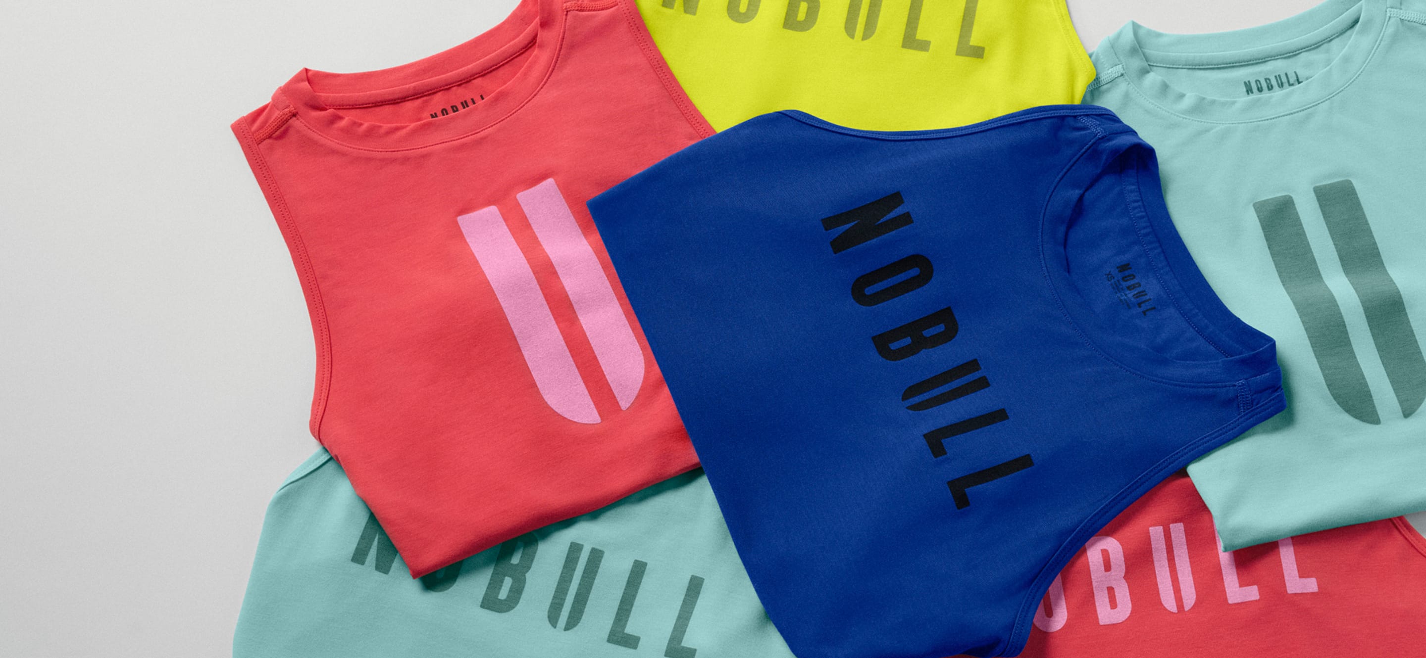 colorful nobull shirts folded on white table top