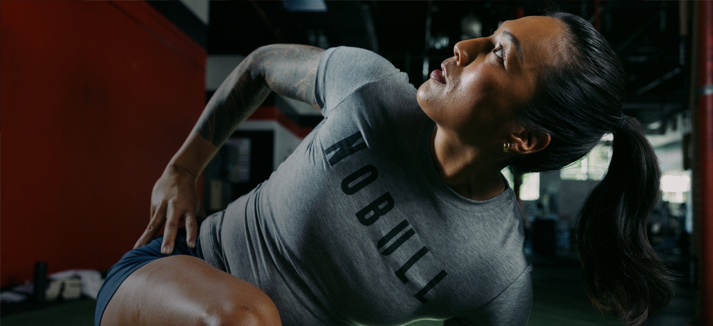 Person exercising in a gym wearing a grey NOBULL tee.