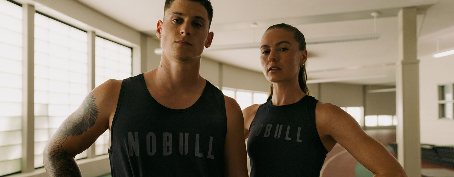 promo - Two people wearing NOBULL tank tops in a gym setting.