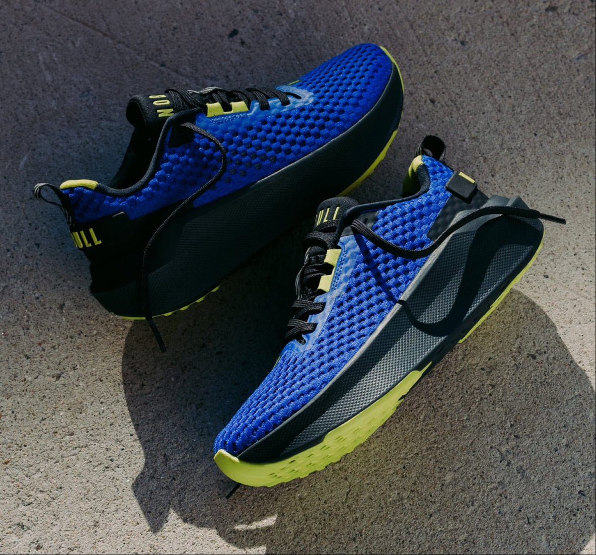 product - A split image showing a runner wearing blue and black running shoes on an outdoor street, alongside a close-up of the same shoes on pavement. The shoes have a bright blue mesh upper, black midsole, and neon yellow outsole.