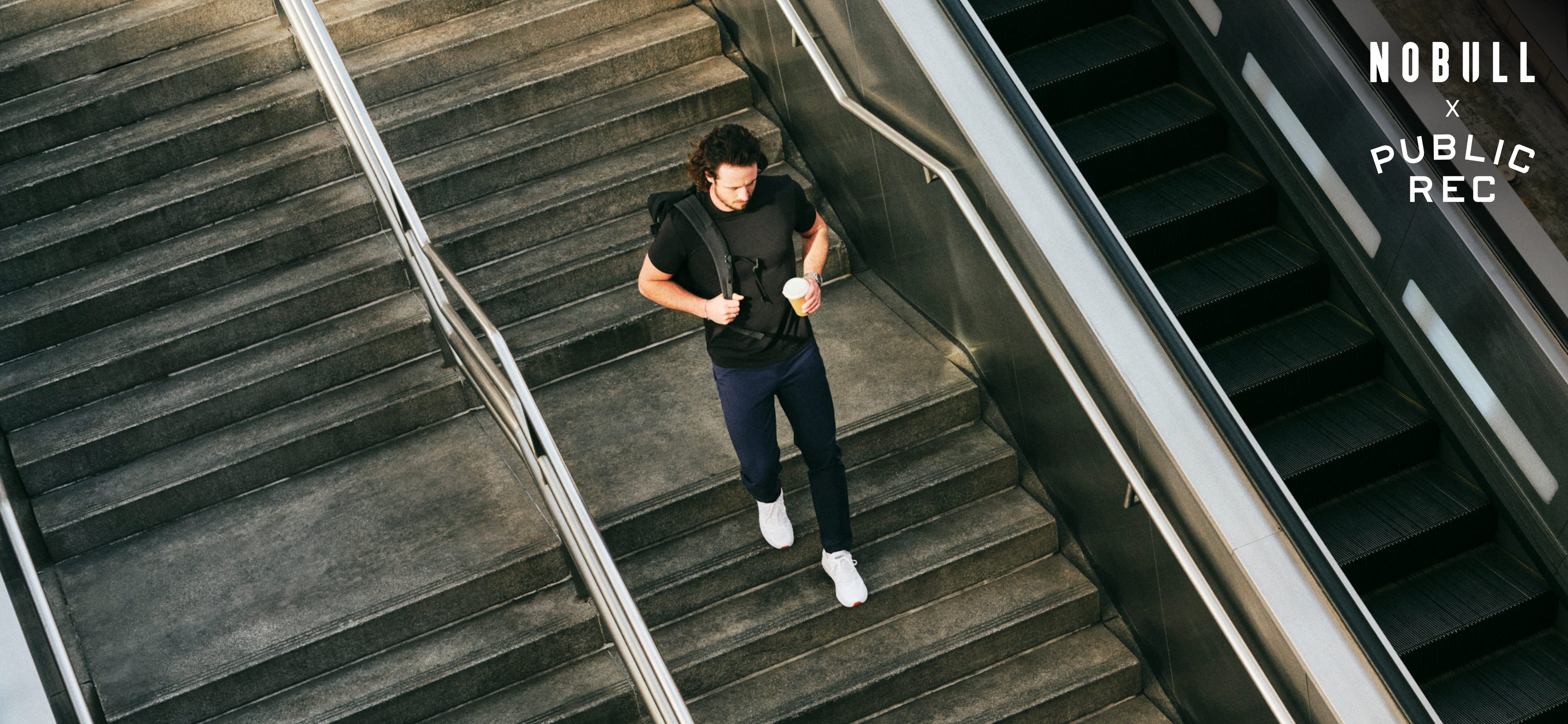 Person standing on a set of stairs with an escalator to the side.