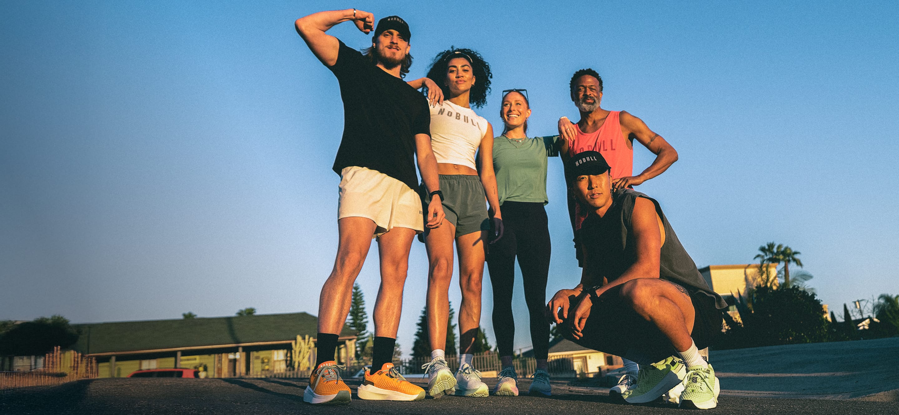 Group of five people posing together outdoors with a clear blue sky.