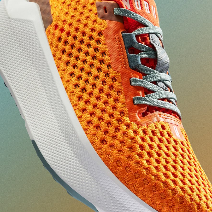 Close-up of an orange and white athletic shoe with a blurred background