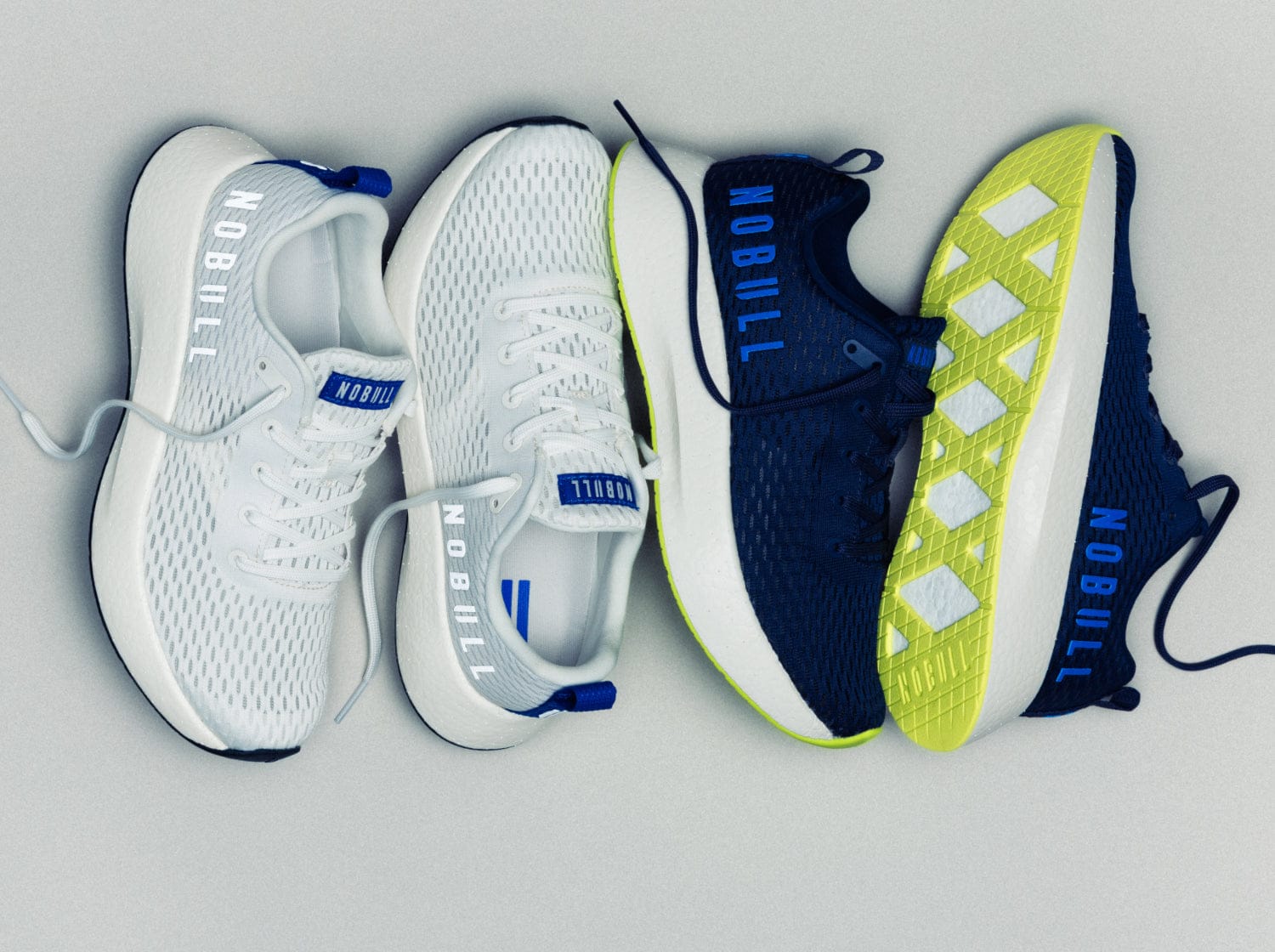 Four running shoes in white, blue, and navy on a gray background