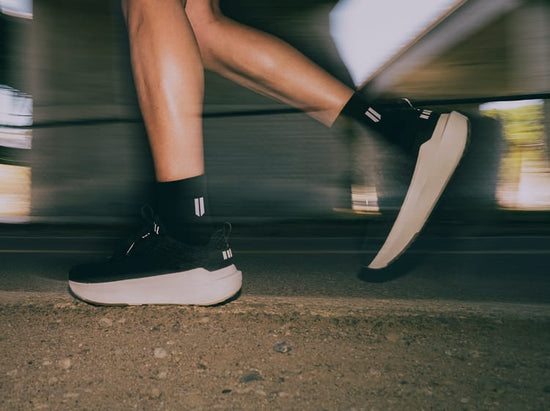 Person riding a bicycle with focus on black shoes and socks.