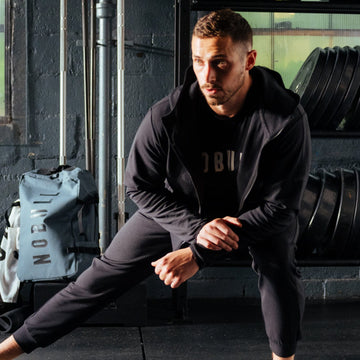 Man wearing black drive joggers and stretching