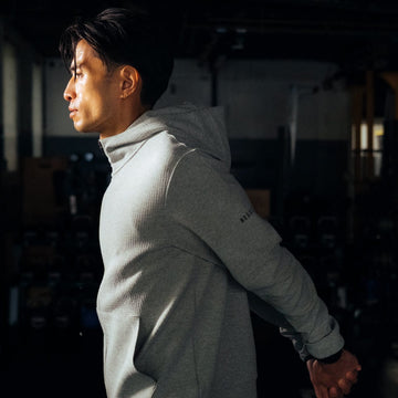Man wearing grey drive zip-up hoodie and stretching