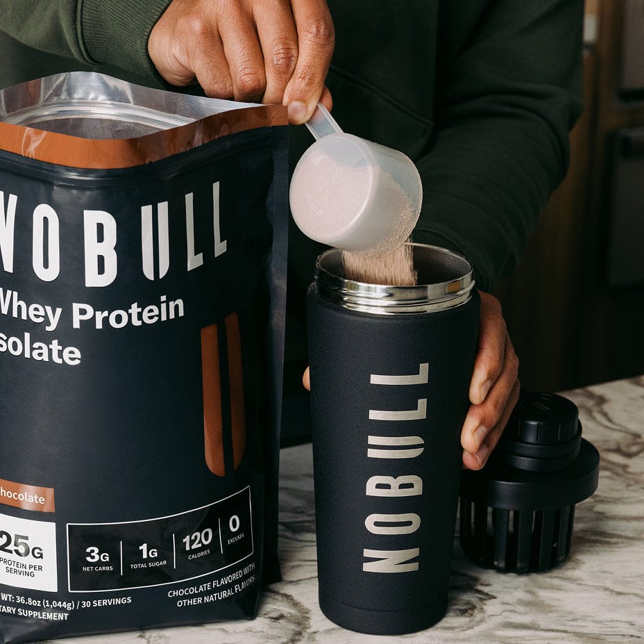 Person pouring Chocolate NOBULL whey protein into a black insulated container.
