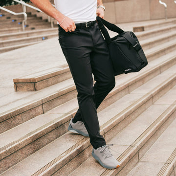 Man walking down stairs wearing black dealmaker 5-pocket pant