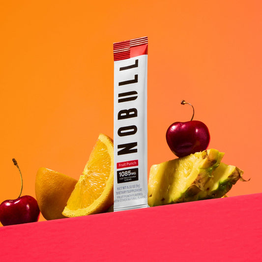 NOBULL fruit punch electrolyte stick with fruits on an orange and pink background