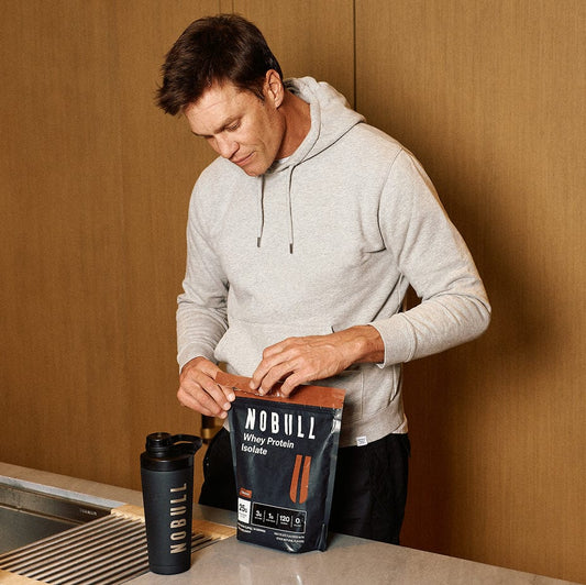 Tom Brady opening a package of Chocolate Whey Protein Isolate
