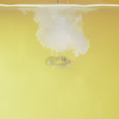 Video of electrolyte powder being mixed in with water on a yellow background